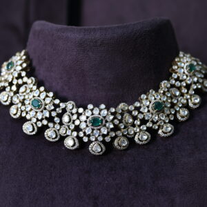 The image showcases a stunning necklace adorned with a cluster of large, faceted gemstones. The necklace appears to be resting on a dark, velvety surface, possibly a jewelry display. The background is blurred, drawing attention to the intricate details of the necklace. Premium Moissanite Choker Necklace