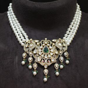 The image showcases a beautiful necklace. It appears to be made with multiple strands of pearls, creating a layered and elegant look. At the center, there is a large pendant adorned with a cluster of sparkling gemstones. The gemstones are arranged in a floral pattern, with a prominent emerald stone in the center. The overall effect is one of luxury and sophistication.
