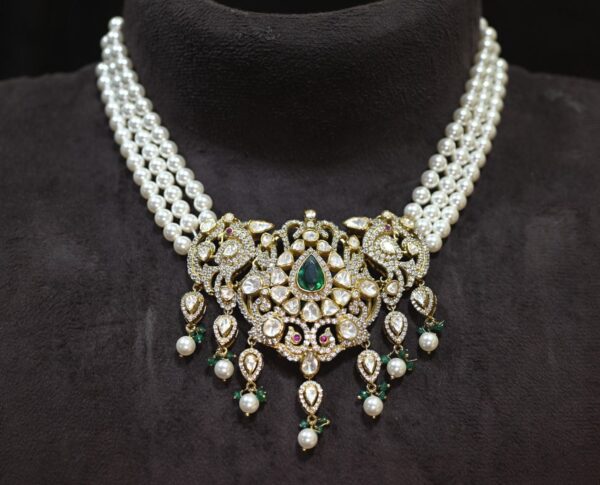 The image showcases a beautiful necklace. It appears to be made with multiple strands of pearls, creating a layered and elegant look. At the center, there is a large pendant adorned with a cluster of sparkling gemstones. The gemstones are arranged in a floral pattern, with a prominent emerald stone in the center. The overall effect is one of luxury and sophistication.