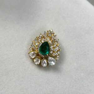 "Gold-toned pendant featuring a pear-shaped green gemstone surrounded by clear teardrop and round-cut stones in an intricate design, displayed on a light background."