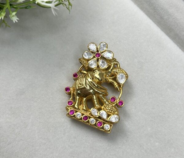 The image showcases a stunning pendant featuring an elephant motif. The elephant, a symbol of wisdom and strength, is intricately crafted and appears to be made of gold. It is adorned with a floral design and studded with sparkling moissanite stones, adding a touch of brilliance and elegance. The pendant rests on a soft, white surface with a few delicate white flowers nearby, creating a visually appealing backdrop.
