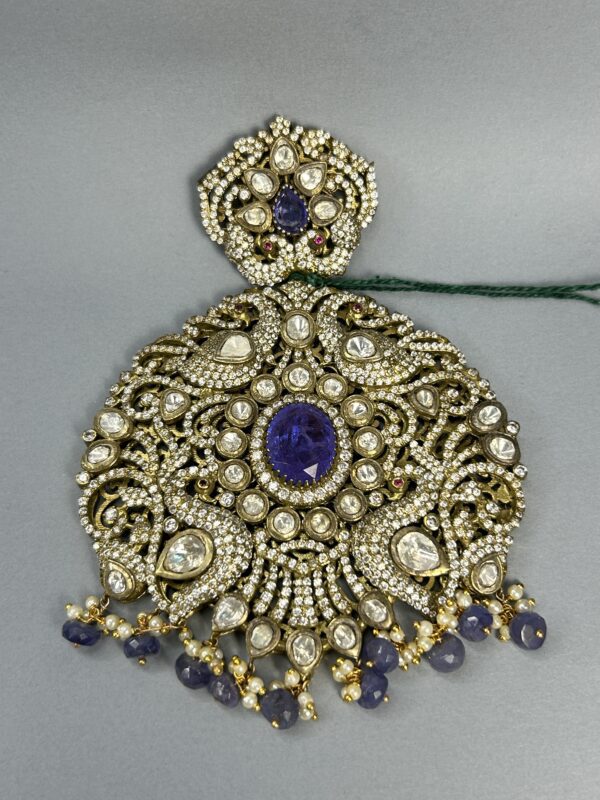 This exquisite pendant features a stunning display of moissanite stones set in a intricate floral design. The centerpiece is a large, oval-shaped blue moissanite, surrounded by a halo of smaller, sparkling moissanite stones. The pendant's frame is adorned with delicate floral motifs and intricate filigree work, creating a luxurious and elegant look.