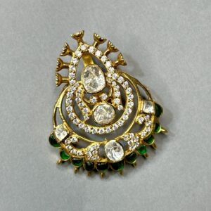 The image appears to be a close-up photograph of a jewelry piece, likely a pendant or brooch. It showcases intricate craftsmanship with a blend of traditional and contemporary elements.