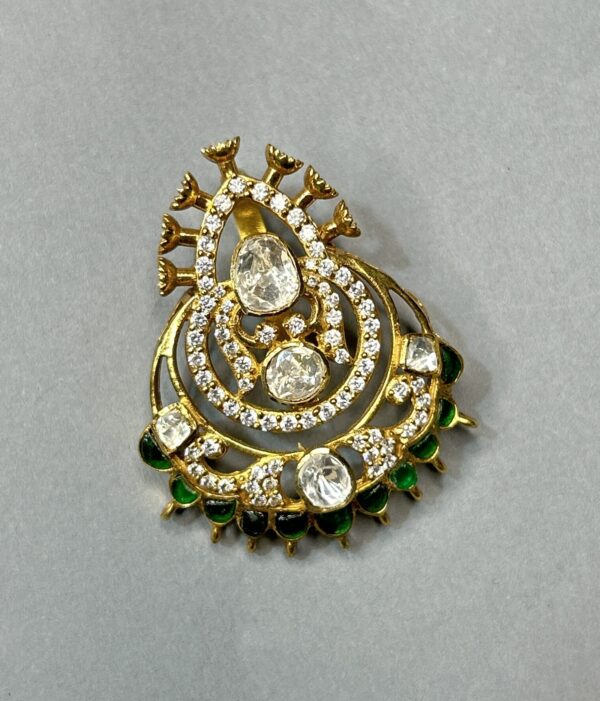 The image appears to be a close-up photograph of a jewelry piece, likely a pendant or brooch. It showcases intricate craftsmanship with a blend of traditional and contemporary elements.