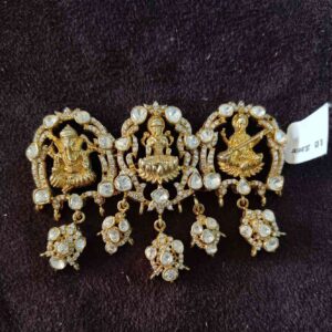 The image shows a necklace with a central pendant featuring three Hindu deities: Lord Ganesha: The elephant-headed god, known for removing obstacles and bringing good luck. Goddess Lakshmi: The goddess of wealth, prosperity, and good fortune. Goddess Saraswati: The goddess of knowledge, music, and the arts.