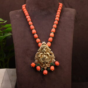 A silver temple pendant depicting a Hindu deity, likely Lord Ganesha. A close-up of a silver pendant with intricate details and colorful gemstones.