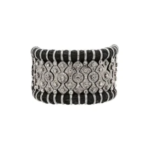 A wide, ornate bracelet featuring uncut Polki diamonds set in a detailed silver or white gold framework. The design incorporates repeating geometric and floral motifs, accented by dark, multi-stranded threads that provide a textural contrast. The bracelet has a traditional and elegant aesthetic.