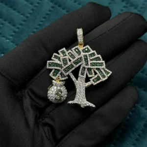 This image shows a luxurious pendant held against a black gloved hand. The pendant is shaped like a stylized tree, with branches filled with green and white sparkling stones. Hanging from one side of the tree is a small money bag charm, also fully encrusted with shimmering stones, symbolizing wealth and prosperity. The entire piece is crafted in 925 sterling silver, with parts of it finished in a gold tone, particularly around the bail (the loop where the chain goes through) and the money bag. The pendant has a bold, flashy, hip hop aesthetic, emphasizing luxury, success, and high fashion.