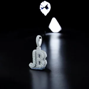 A diamond-studded "JB" pendant crafted from 925 silver, showcased under dramatic lighting on a sleek black background.